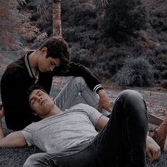 two young men are laying on the ground