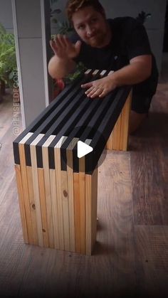 a man sitting on top of a bench made out of strips of black and white wood