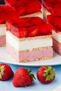 strawberry cheesecake with raspberry filling on a white plate next to strawberries