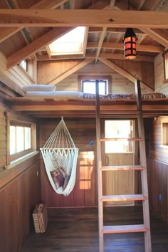 a hammock hanging from the ceiling in a room with wood floors and walls