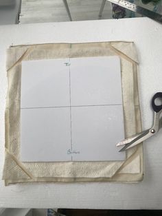 a pair of scissors sitting on top of a piece of fabric next to a cutting board