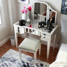 a white vanity table with a mirror and stool