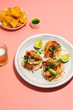 three tacos on a white plate with lime wedges and guacamole