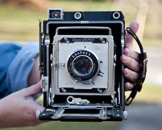 an old camera being held by two hands