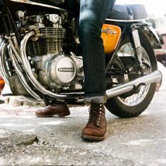 a man sitting on the back of a motorcycle with his feet propped up in front of him