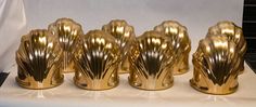 five golden vases sitting on top of a white table