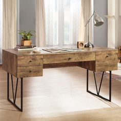 a wooden desk sitting in front of a window next to a lamp and potted plant