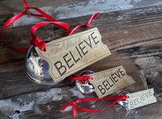 two bells with red ribbon and believe tags attached to them