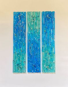 three pieces of art made out of glass on a white surface with blue and green colors