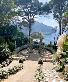 an outdoor ceremony setup with white flowers and greenery on the ground, surrounded by trees