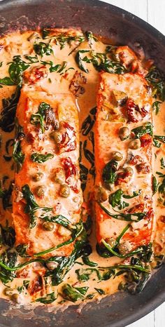 a pan filled with meat covered in sauce and spinach on top of a wooden table