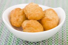 a white bowl filled with fried food on top of a green and white table cloth