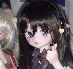 a close up of a doll with long hair and big eyes holding a small object