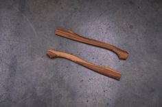 two wooden spoons sitting next to each other on top of a cement floor,