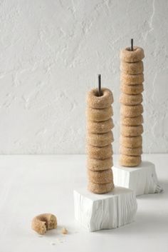 two tall candles sitting next to each other on top of a white tablecloth covered surface