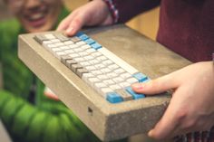 a person holding a keyboard in their hands and smiling at the camera while another person looks on