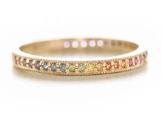 a yellow gold band with multi colored stones