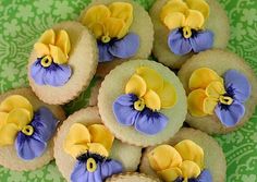 some cookies with yellow and purple flowers on them are sitting on a green tablecloth