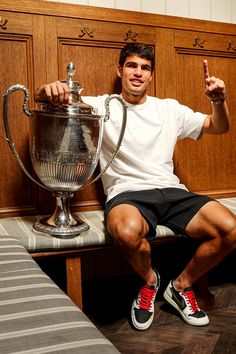 a man is sitting on a bench with a trophy and giving the thumbs up sign