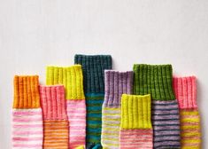 a group of multicolored knitted socks sitting next to each other on top of a white surface