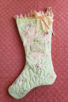 a green christmas stocking with pink flowers and a bow on it's side