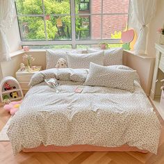 a bed in a bedroom with white and pink comforter, pillows and stuffed animals