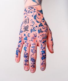 a person's hand with blue tattoos and writing on the palm, all over their body