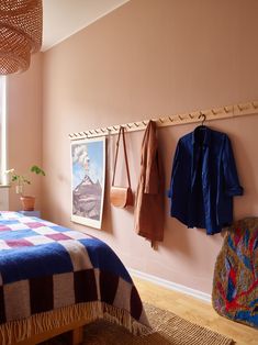 a bed room with a neatly made bed and some hanging items on the wall next to it