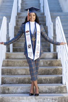 a woman wearing a graduation cap and gown standing on steps with her arms out in the air