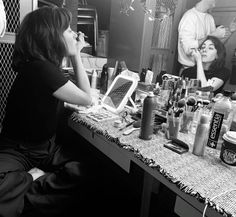 two women sitting at a counter with bottles and hairdryers in front of them