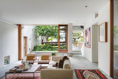 a living room filled with furniture next to a window covered in plants and greenery