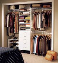 an organized closet is shown with clothes and suitcases on the floor, along with a bed