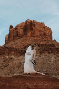 a bride and groom kissing in the desert