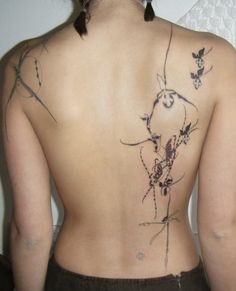 the back of a woman's body with tattoos on it