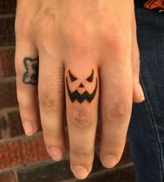 a person's hand with a tattoo on it and a jack o lantern ring