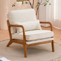 a white chair sitting on top of a wooden floor next to a tree in a living room