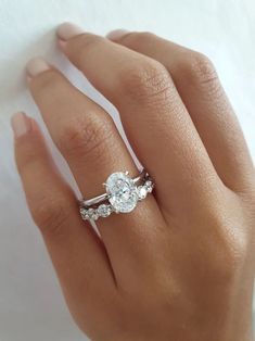 a woman's hand with a diamond ring on top of her finger and an engagement band