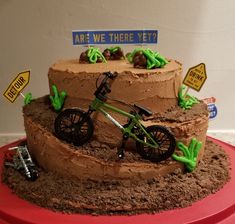 there is a cake that looks like a bike on top of dirt and dirt mounds