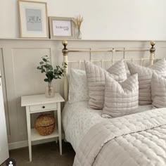 a white bed sitting next to a small table with a potted plant on it