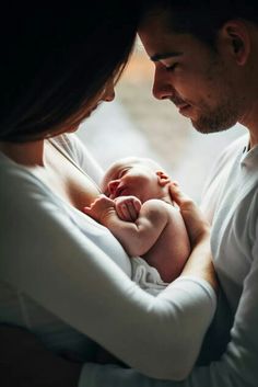 a man and woman holding a baby in their arms