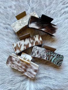 several different colored hair clips laying on top of a fur covered surface with white and brown designs