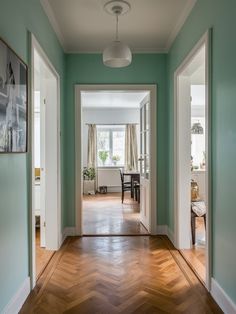 an empty room with green walls and wood floors is seen from the hallway to the dining area