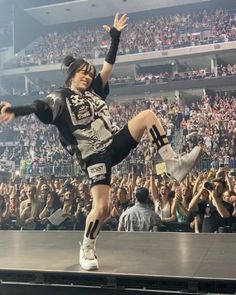 a man in black and white shirt doing a trick on stage with his legs spread out