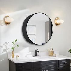 a white bathroom with black vanity and round mirror