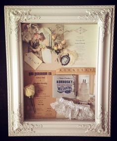 a white frame with some pictures and flowers in it on a table next to other items