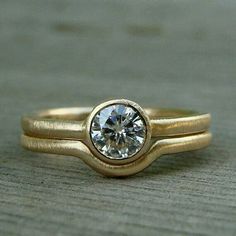 a gold ring with a white diamond on the top and bottom, sitting on a wooden surface