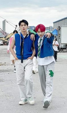 two young men walking down a street next to each other