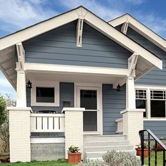 a blue house with white trim on the front porch and stairs leading up to it