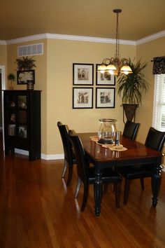 a dinning room table with chairs and pictures on the wall behind it in a home