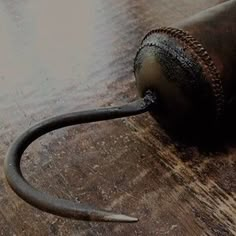 a close up of a metal object on a wooden table with a hammer in it